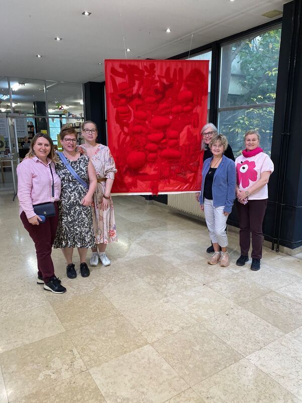 1000014727.jpg A group of women, red piece of art.