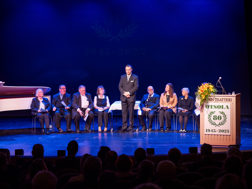 Ansiomerkkien saajat ja rehtori-toiminnanjohtaja Alexander Bruk Porin Teatterin lavalla Otsolan 80-vuotisjuhlassa.