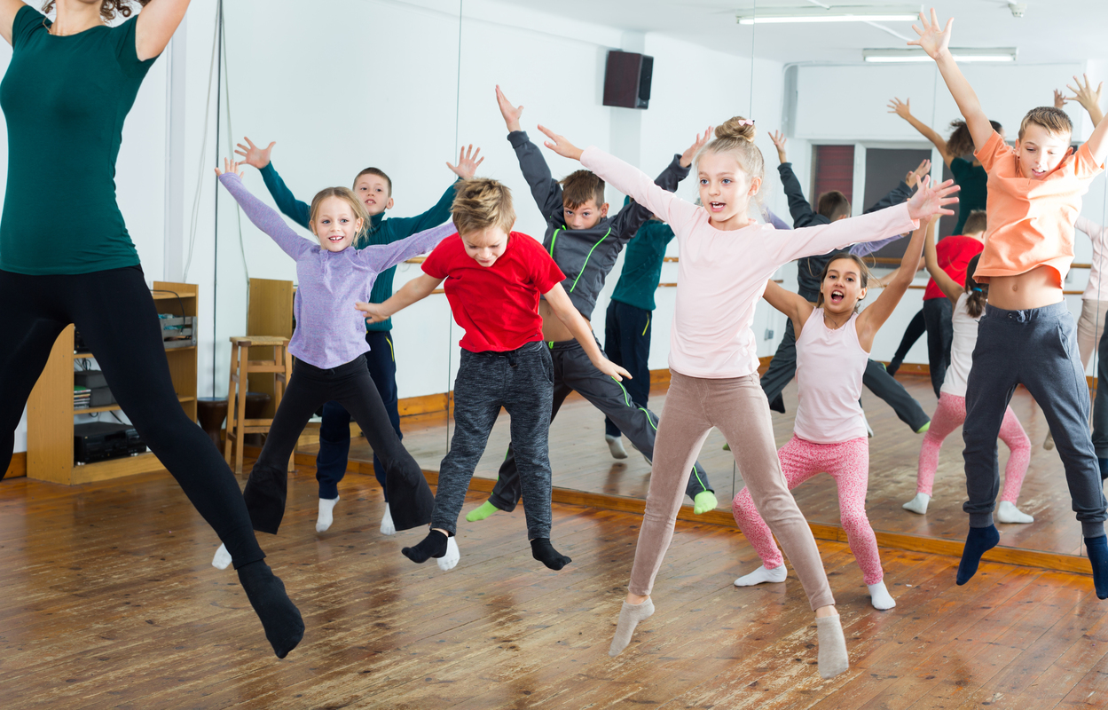 Lapsiryhmä tekee haarahyppyliikettä tanssisalissa.