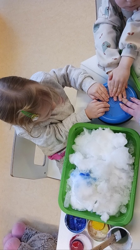 Lapset käyttävät ääninappulaa lumimaalauksessa