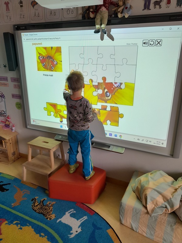 Lapsi tekemässä smart-taululla palapeliä
