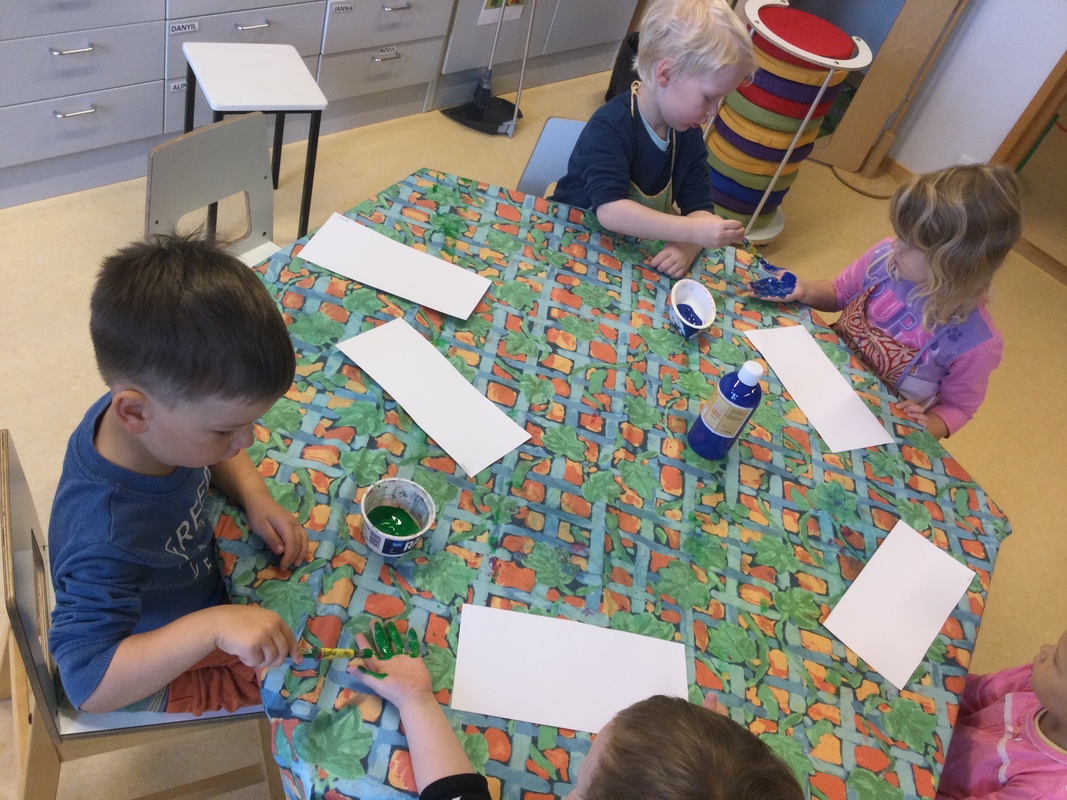 Lapset maalaavat toistensa käsiä.