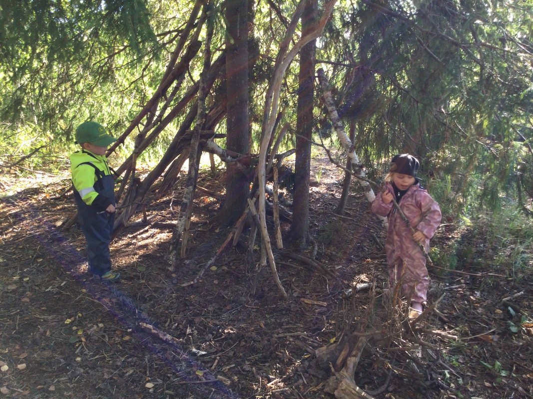 Lapsia metsässä rakentamassa majaa.