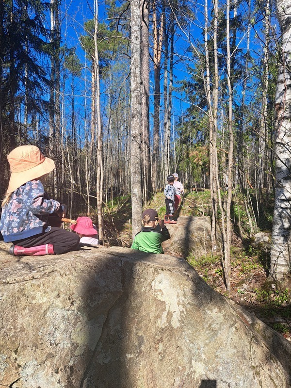 Lapsia istumassa kivellä metsässä