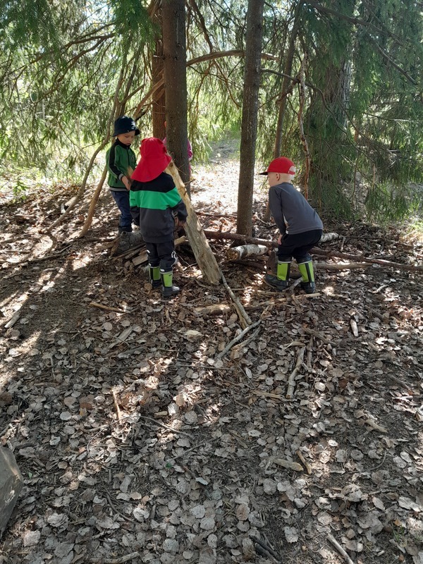 Lapsia metsässä rakentamassa majaa
