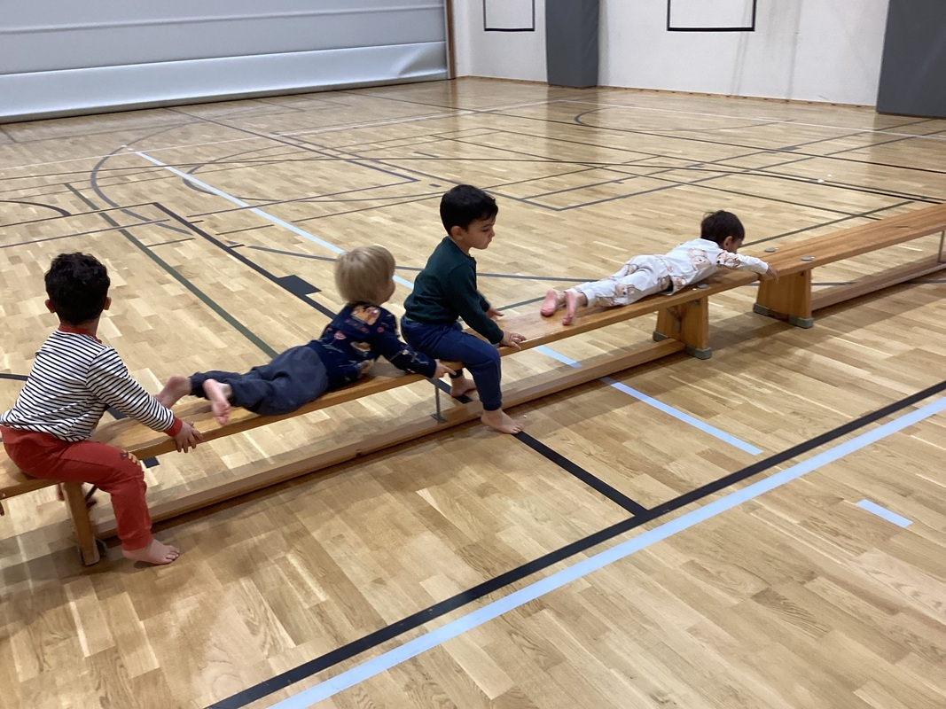 Lapset vetävät penkillä itseään eteenpäin vatsallaan