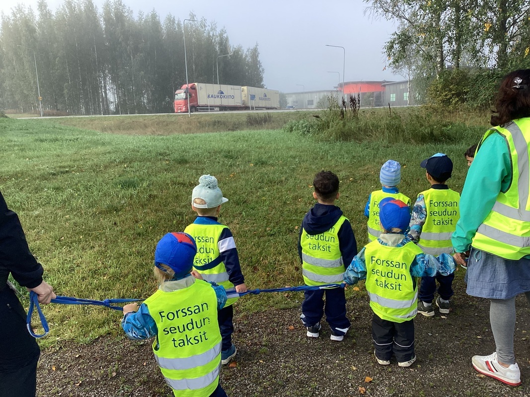 Lapset seuraavat rekka autoja tiellä