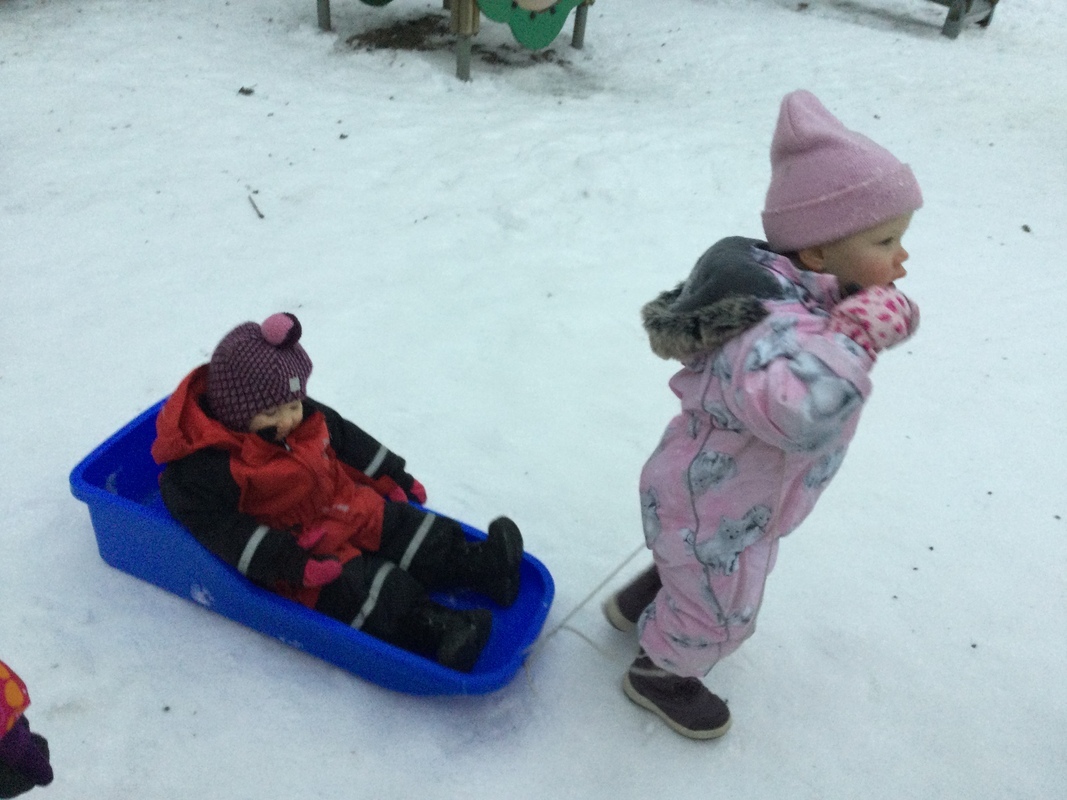 Lapsi vetää kaveria pulkassa