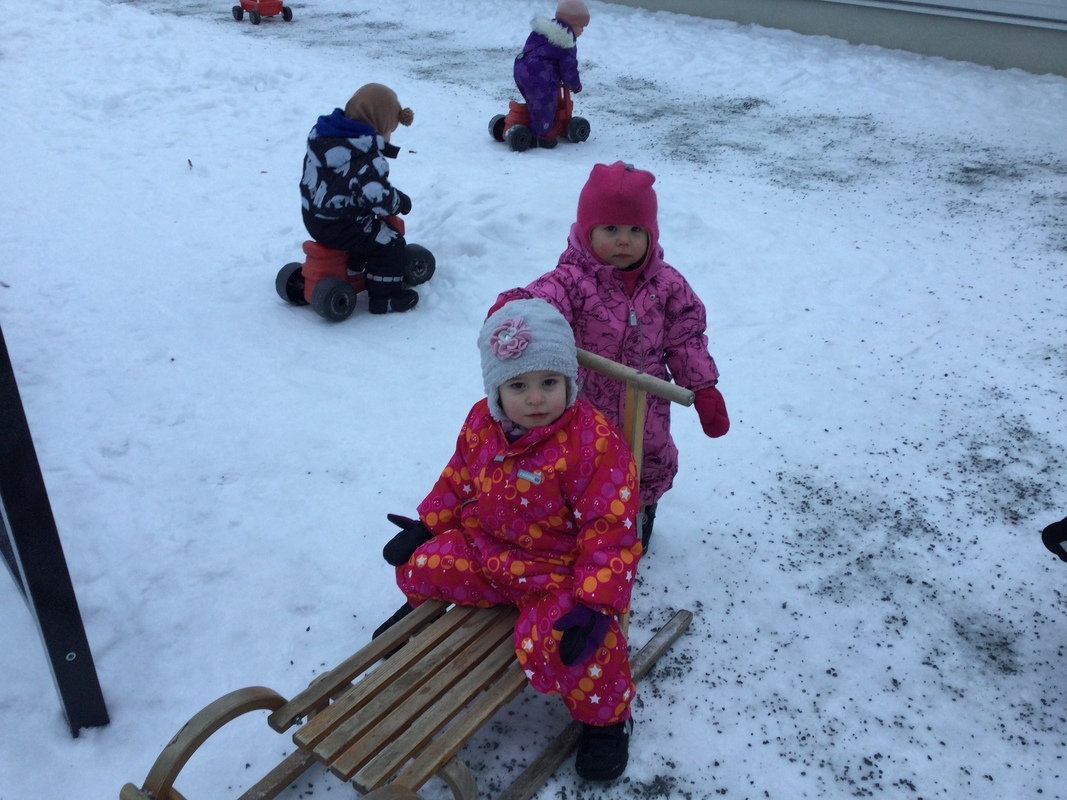 Lapsi työntää kaveria kelkassa