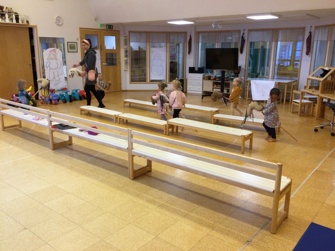 Lapset pujottelevat rataa keppihevosilla aikuisen kanssa