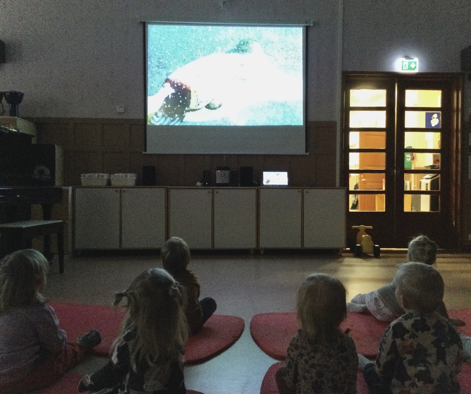 Lapset katsomassa elokuvaa päiväkodin jumppasalissa