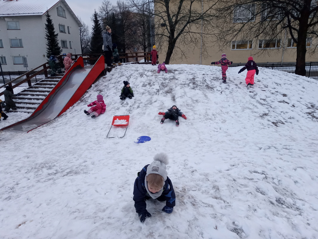 Lapset laskevat mäkeä päiväkodin pihalla