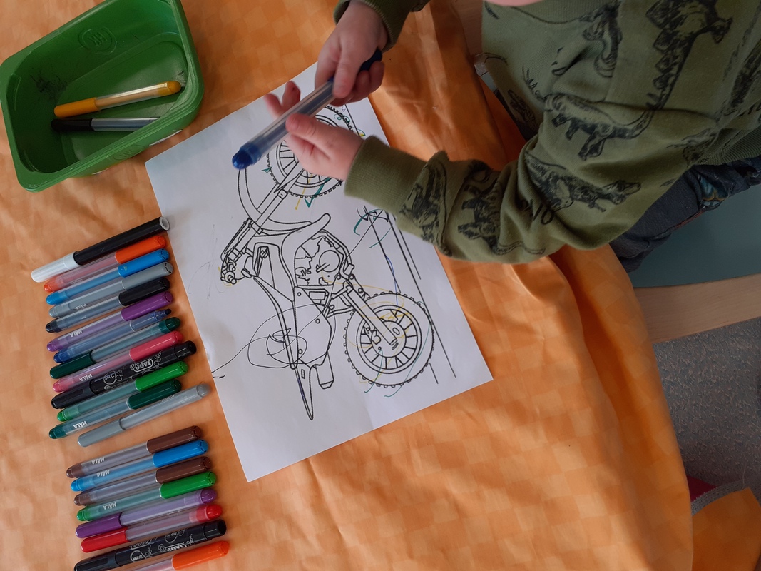 Lapsi värittämässä moottoripyörän kuvaa.