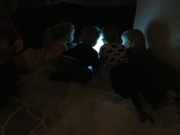 Lapset katsovat valoakvaariota pimeässä huoneessa.