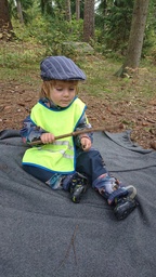 Lapsi soittaa kepeillä metsässä.