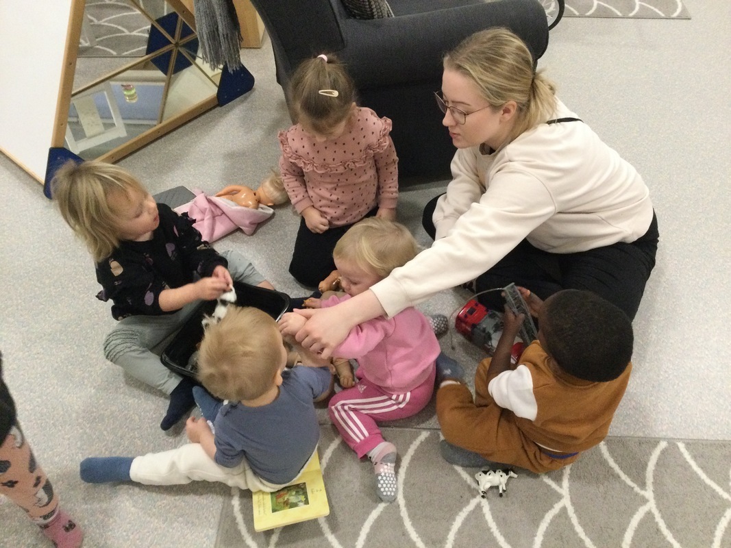 Lapset leikkivät yhdessä aikuisen ohjatessa.