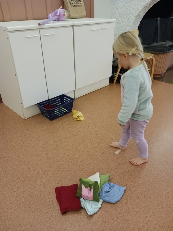 Lapsi heittää hernepusseja koriin.