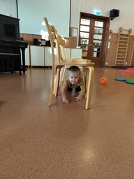 Lapsi ryömii tuolien alta.
