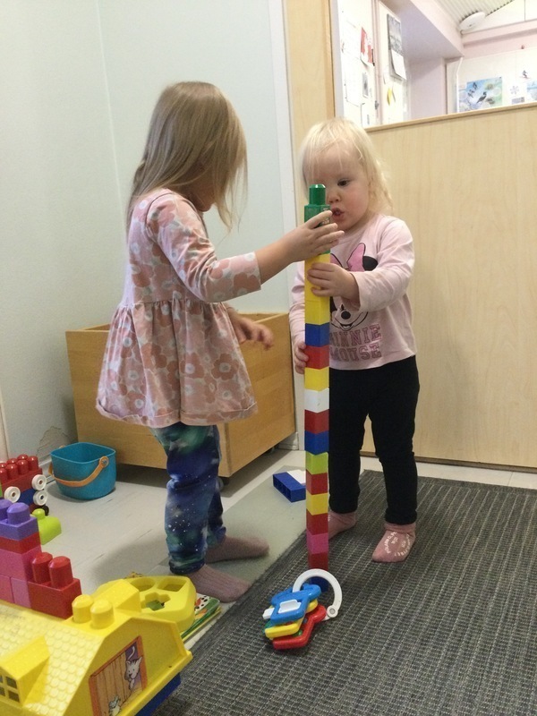 Lapset rakentavat muovipalikoista korkeaa tornia.