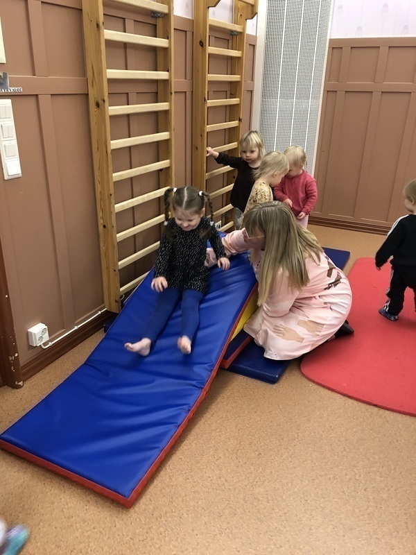 Lapset liukuvat patjamäkeä salissa.