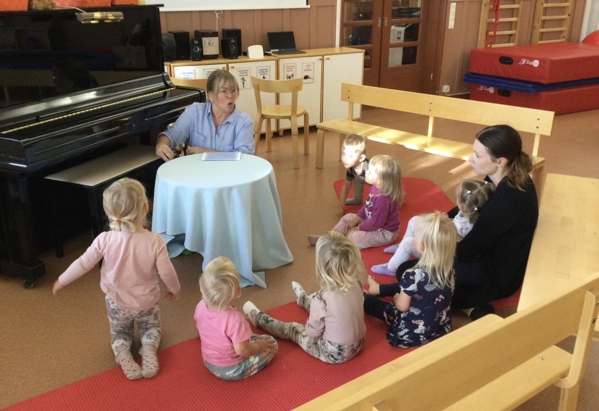 Lapset kuuntelevat pöytäteatterisatua salissa.