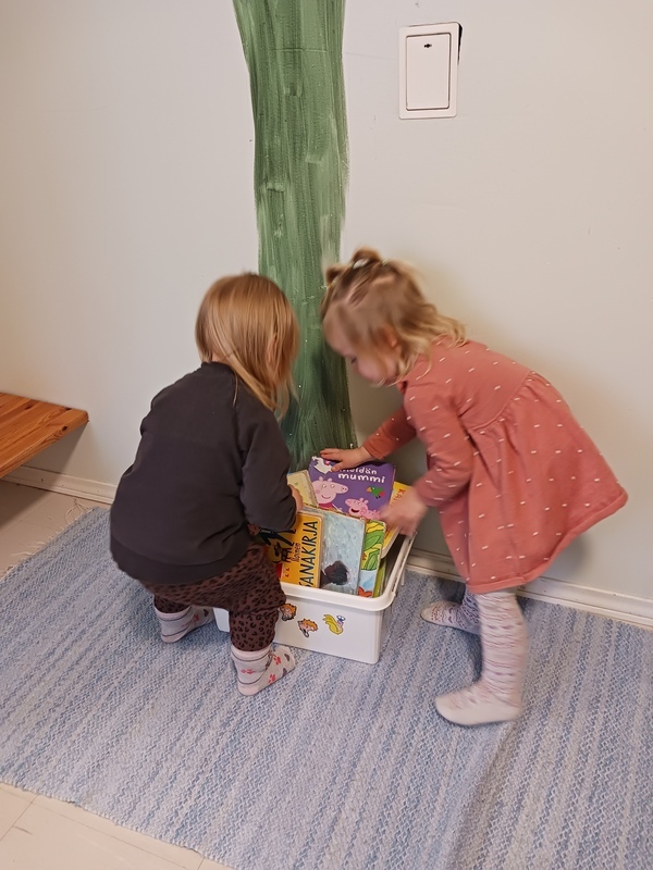 Lapset keräävät kirjoja laatikkoon.