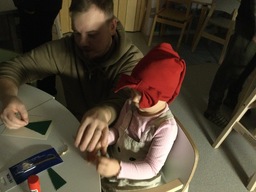 Lapsi askartelee isän kanssa joulukorttia.