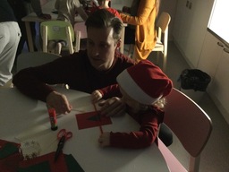 Lapsi askartelee isän kanssa joulukorttia.