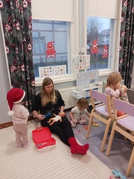 Lapset leikkivät lääkäriä aikuisen ohjauksessa.