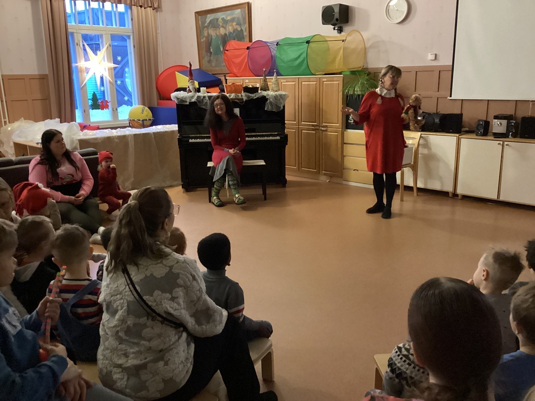 Lapset istuvat salissa ja osallistuvat jouluiseen laulutuokioon.