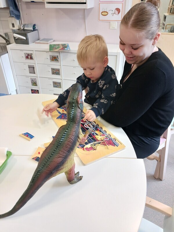 Lapsi tekee palapeliä aikuisen sylissä.