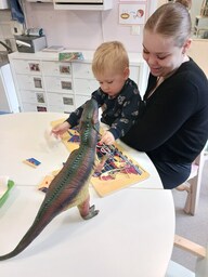 Lapsi tekee palapeliä aikuisen sylissä.
