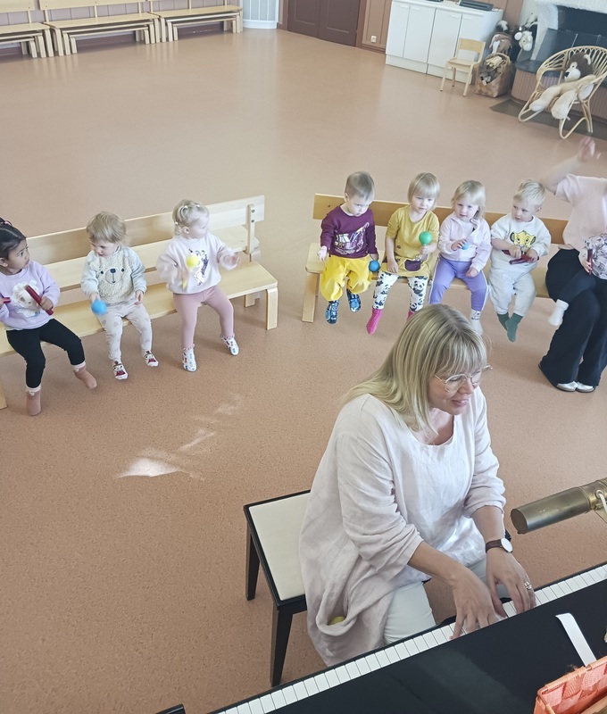 Lapset soittavat marakasseja ja kapuloita piano tahdissa.