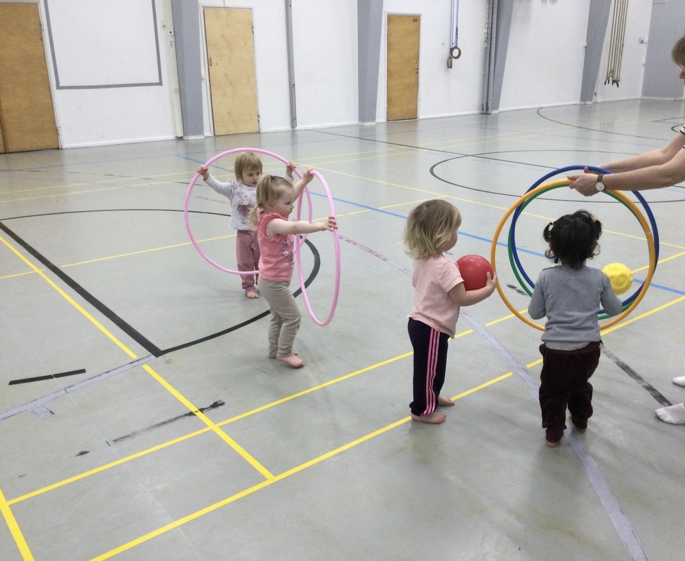 Lapset leikkivät jumppavanteilla liikuntasalissa.