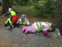 Lapset leikkivät ison kiven päällä.