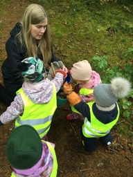 Lapset tuovat aikuiselle keräämiään metsän tuotteita.