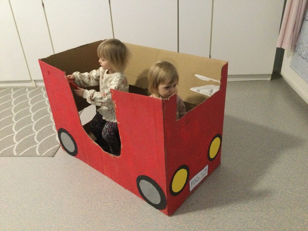 Lapset ovat pahvipaloauton sisällä ajelemassa.