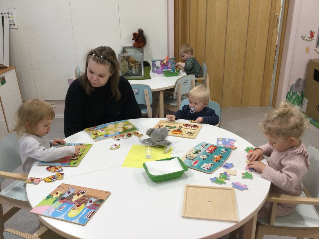 Lapset tekevät palapelejä pöydän ääressä.