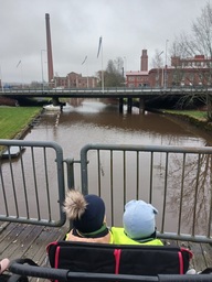 Lapset katselevat sillalla jokimaisemaa.