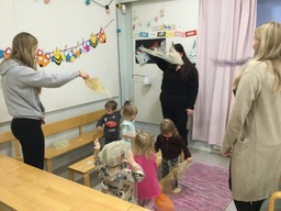 Lapset heiluttavat huivia musiikin tahdissa.