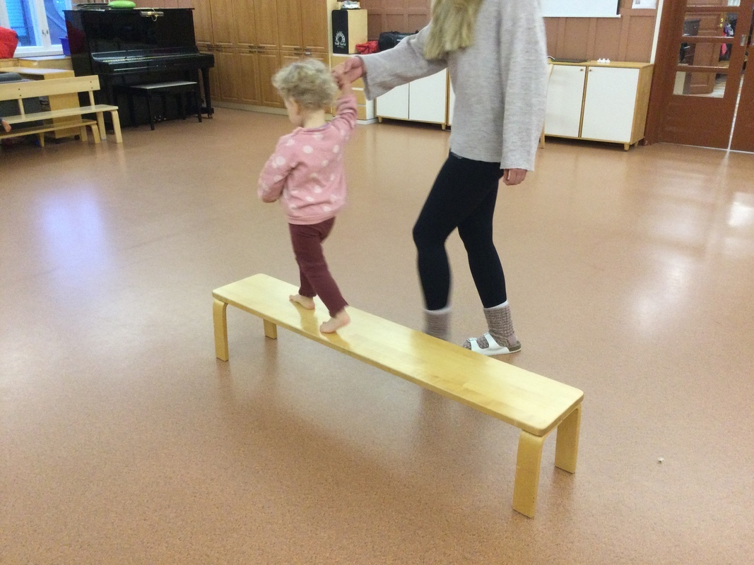 Lapset tasapainoilevat penkin päällä.