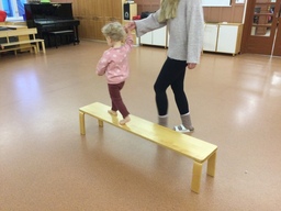 Lapset tasapainoilevat penkin päällä.