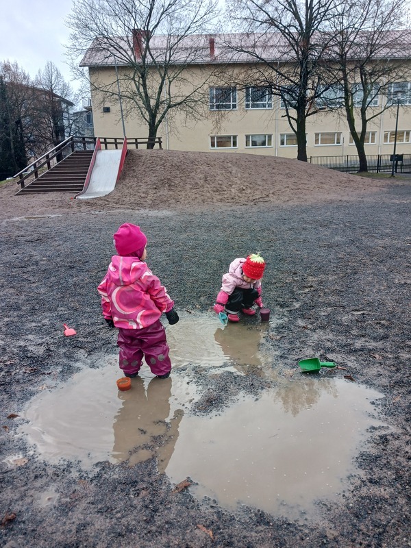 Lapset leikkivät vesilätäkössä.