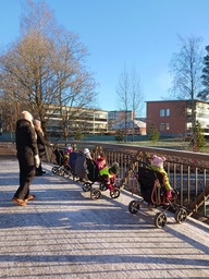 Lapset katselevat sillalla joelle päin syksyisessä säässä.