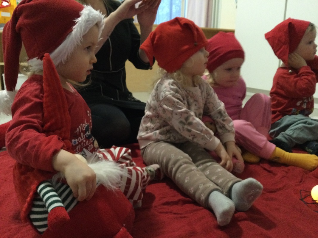 Lapset istuvat piirissä tonttulakit päässä.