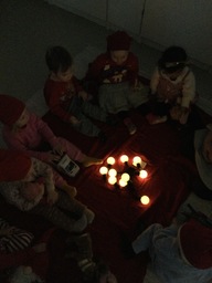 Lapset istuvat hämärässä valojen ympärillä.