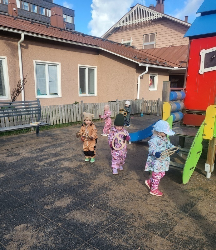 Lapset leikkivät puisilla autonrateilla ulkona.