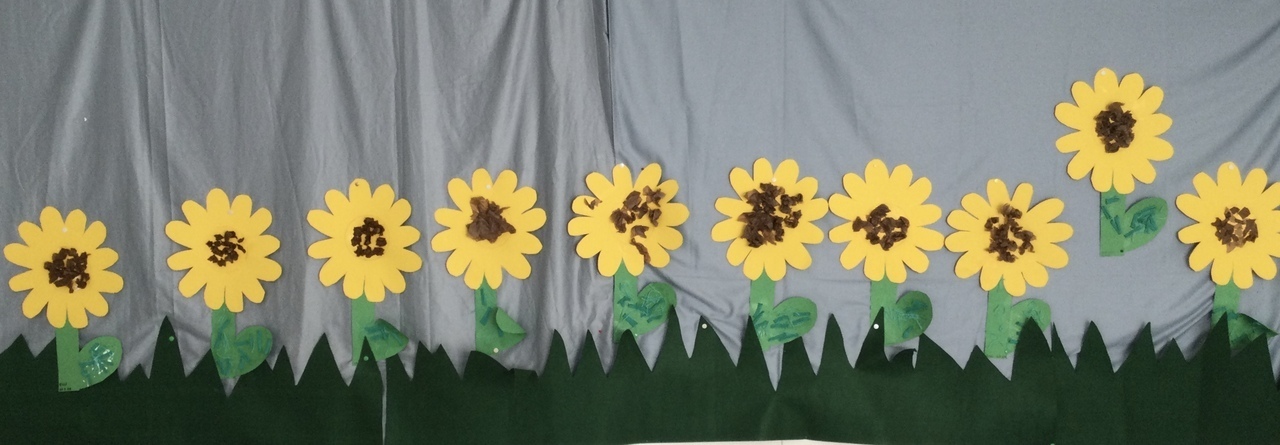 Lasten askartelemia auringonkukkia seinällä.