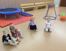 Lapset istuvat lattialla ja kuuntelevat aikuisen kertomaa.