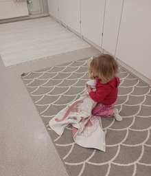 Lapsi tuudittaa vauvanukkea uneen.